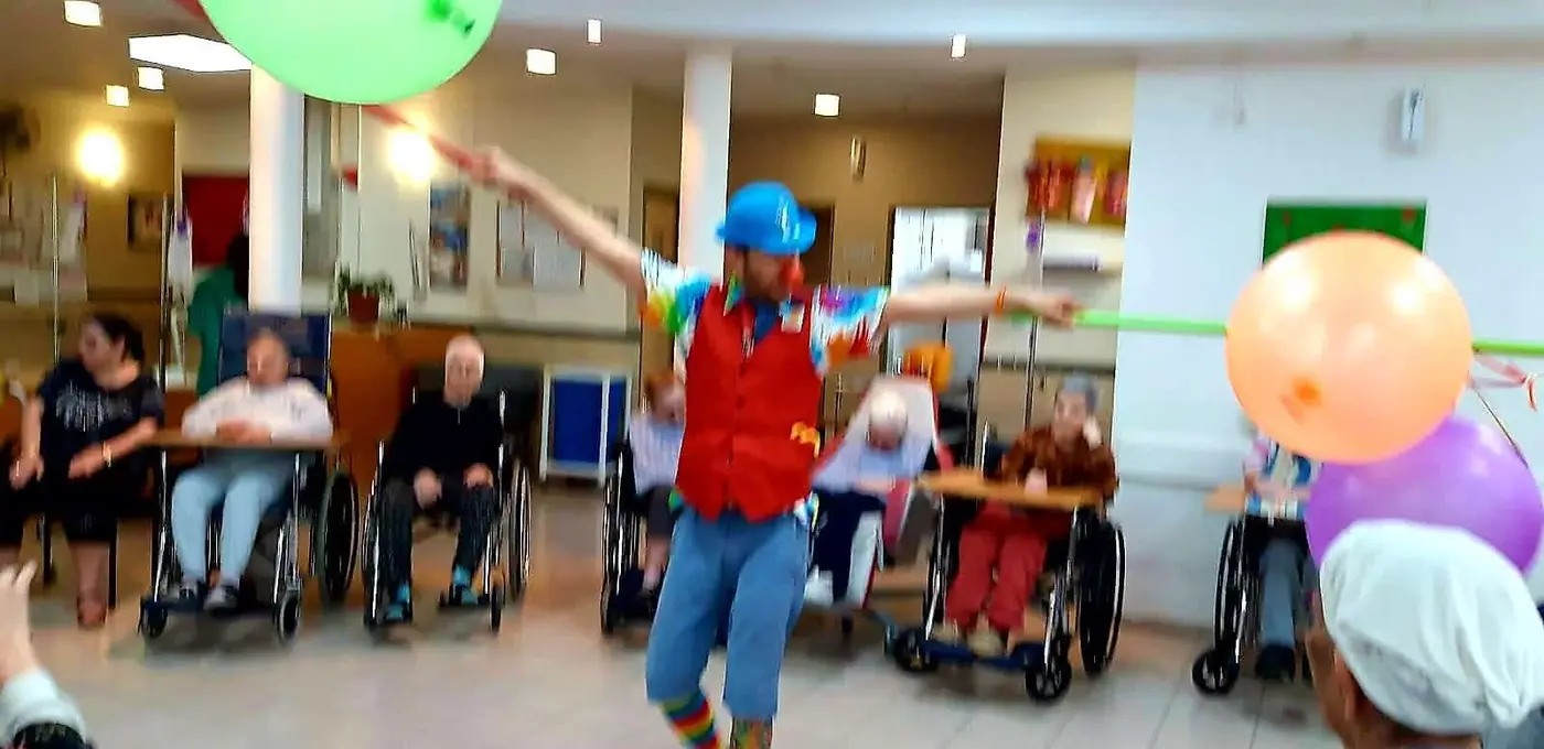 ליצן עם בלונים מול דיירים בכיסאות גלגלים