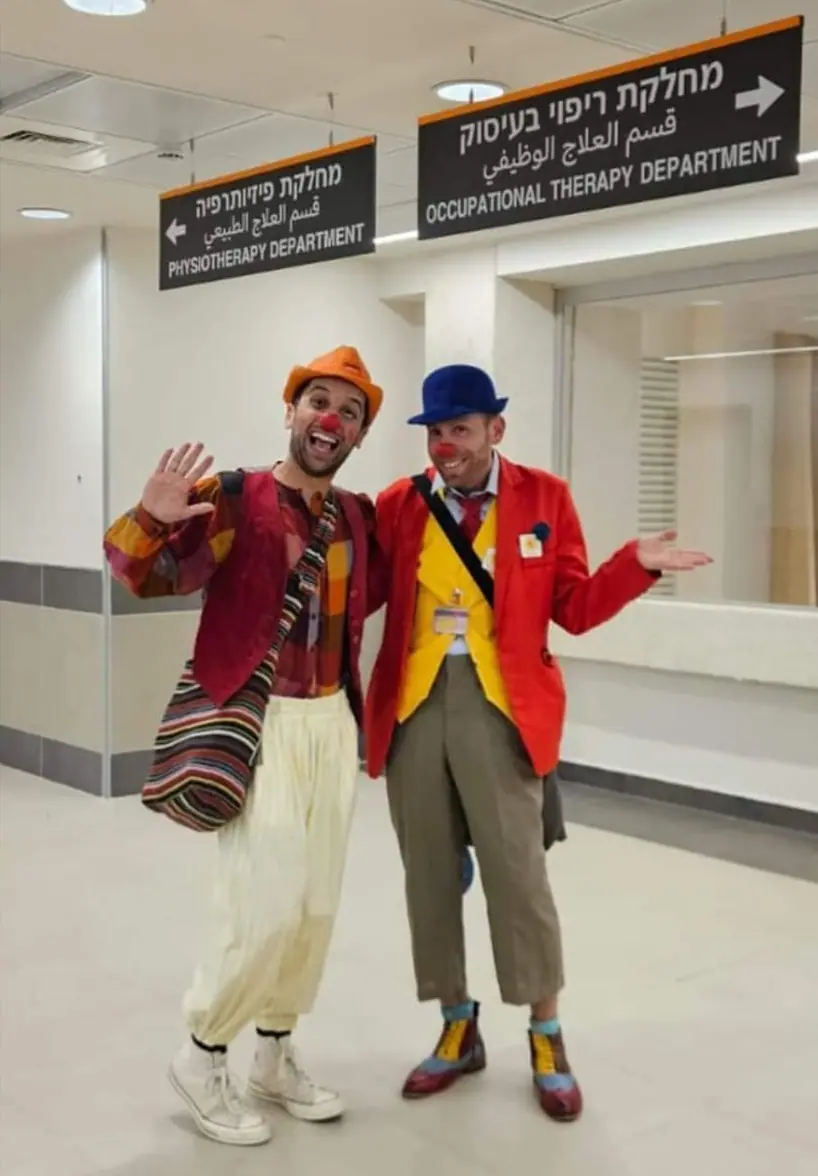 שני ליצנים רפואיים ליד שלט מחלקה בבית חולים